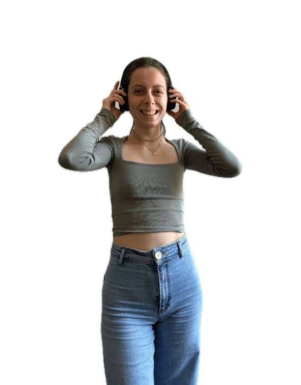 Femme avec casque audio, en top gris et jean, en train d’écouter attentivement, sourire franc.